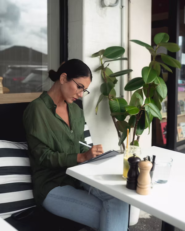 Small business owner reviewing vendor bills on a laptop at a café table